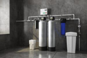 A Pronto Plumbing water filtration and softener system features dual metal tanks, control panel, and brine tank in a utility room.