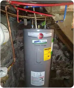 A gray Rheem water heater, professionally installed by the Pronto Plumbing, Heating, Air, and Drains team, stands in a basement with exposed stone walls. Various pipes are connected above, showcasing the quality and reliability of our services in maintaining home comfort systems.